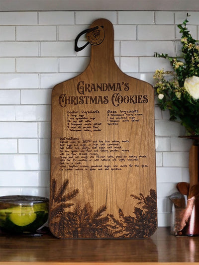 Wooden cutting board with an engraved recipe titled Grandma&#39;s Christmas Cookie featuring detailed instructions and ingredients for cookies and glaze.