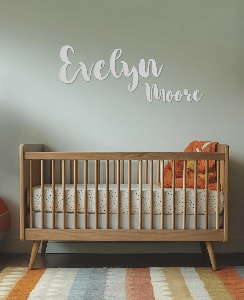 A nursery with &quot;Evelyn Moore&quot; in elegant white script above a wooden crib.