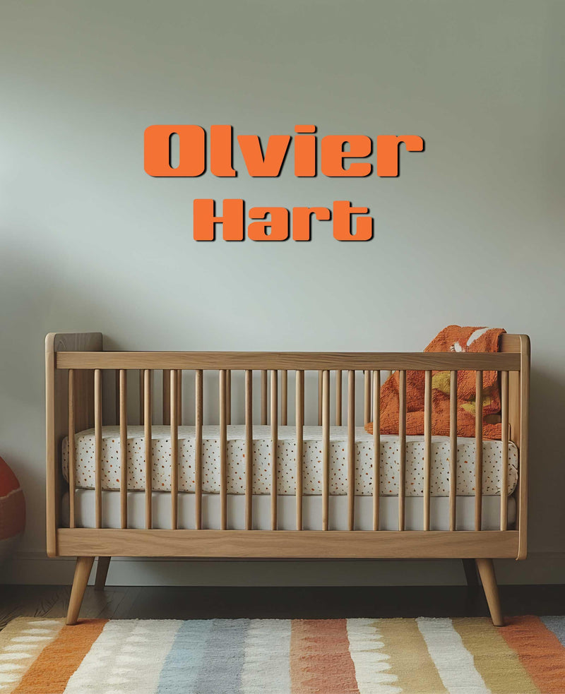 A nursery with &quot;Oliver Hart&quot; in bold orange lettering above a wooden crib.