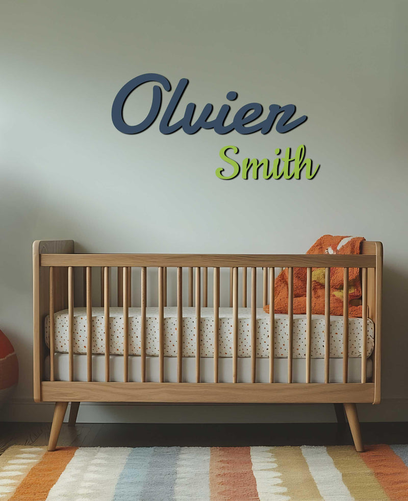 A nursery featuring &quot;Oliver Smith&quot; in navy and green script above a wooden crib.